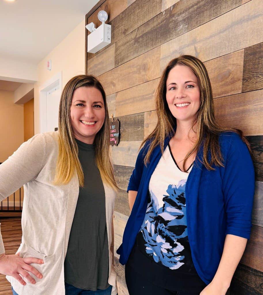 Amanda DeCorte, office manager, and Linda Kelly by the wood wall at the clinic